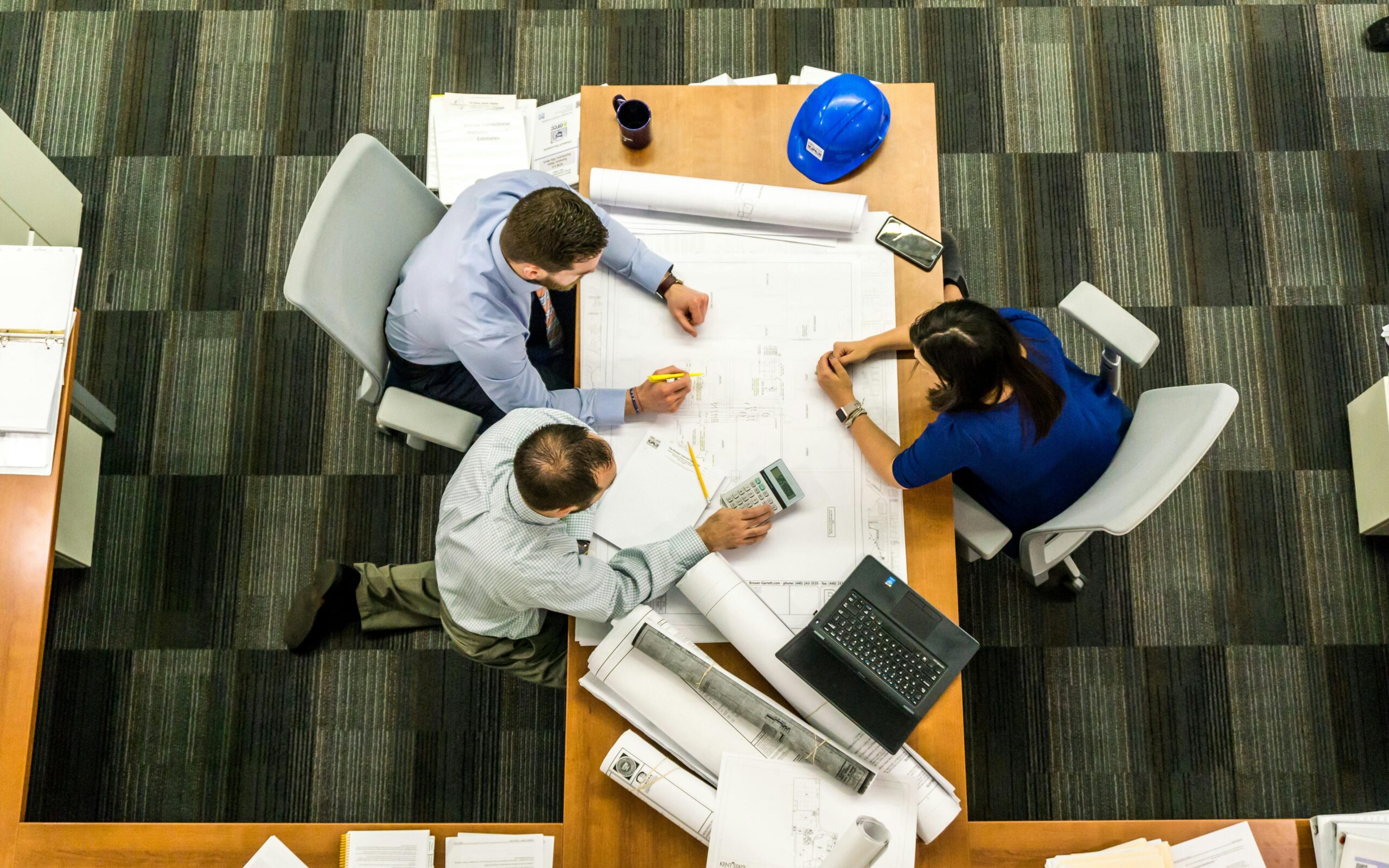 Three people working over a schematic on a desk