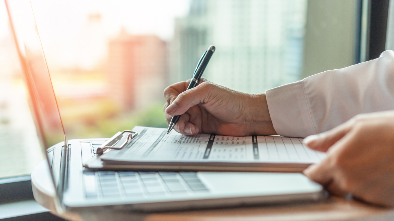 Person writing on a form on a clipboard